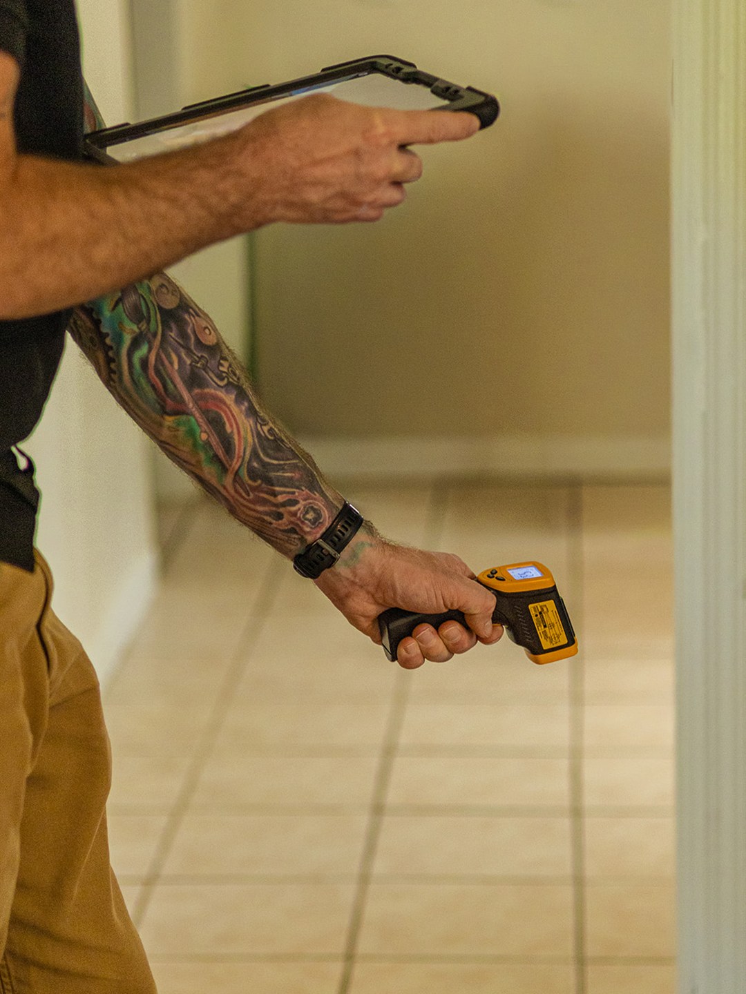 Frame inspector holding a tablet and an infrared thermometer