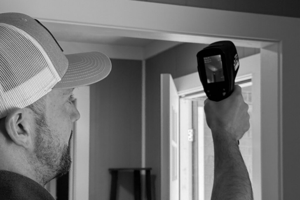 Frame inspector scanning a doorway with a thermal imaging camera